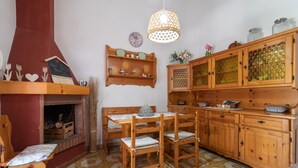Uma cozinha acolhedora com armários de madeira, lareira e uma mesa de jantar com cadeiras.