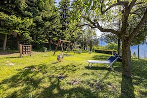 Un espace extérieur verdoyant avec une balançoire, un banc et une structure en bois.