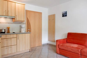 Una cocina con armarios de madera, una cafetera y un sofá rojo en un rincón.