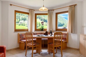 Un comedor con una mesa, sillas y vistas a un paisaje boscoso a través de amplios ventanales.