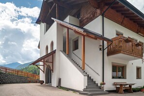 Ein zweistöckiges Gebäude mit einem hölzernen Balkon, einer Treppe und einer Steinmauer.