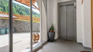 A modern building entrance with a stone wall, a wooden fence, a potted plant, and a door. - Apartment 'Bergerhof 3' with Mountain View, Shared Garden and Wi-Fi (Sarentino)