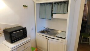 Une cuisine compacte équipée d’un four à micro-ondes, d’un évier et de placards.