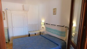 Une chambre à coucher avec un lit, une table de chevet, une lampe, une armoire et un tableau au mur.