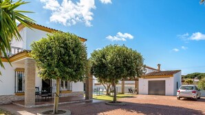 Il s’agit d’une propriété résidentielle dotée d’une allée pavée, d’un garage et d’un espace patio aménagé avec du mobilier d’extérieur.