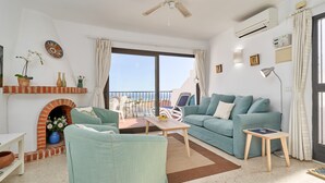 Una sala de estar con sofá, sillones, una mesa de centro, chimenea y un balcón con mobiliario exterior.