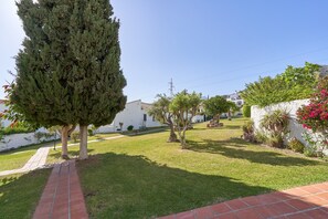 Un quartiere residenziale con un vialetto lastricato, un alto sempreverde e un edificio bianco con tetto in tegole.