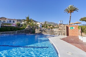 Una piscina con acqua cristallina, circondata da muri in pietra e una palma.
