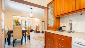 A kitchen with wooden cabinets, a dishwasher, and a dining area with chairs and a table.