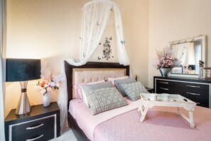 Une chambre à coucher avec un lit à baldaquin, des tables de chevet, une commode et un miroir.