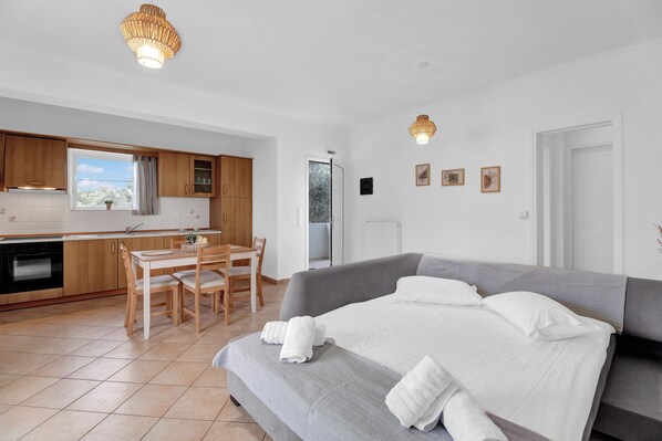 Ein modernes Zimmer mit einem Bett, einem Esstisch und einer Küchenzeile.