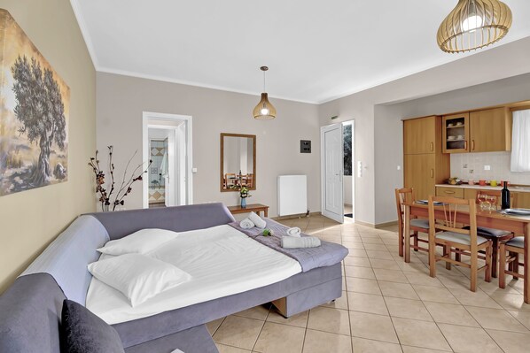 A modern bedroom with a bed, a dining area, and a kitchen.