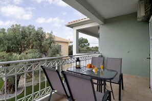Un balcon avec une table, des chaises et un saladier rempli de fruits et de jus.
