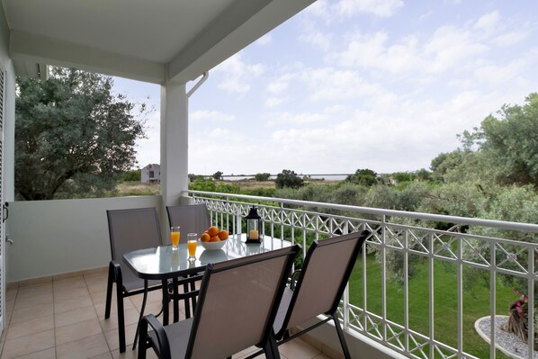 Un balcon avec une table et des chaises, un verre de jus d’orange, un saladier rempli d’oranges et une lanterne.