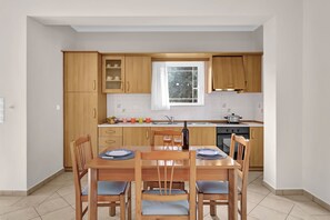 Une cuisine compacte avec des meubles en bois, une fenêtre et une table à manger pour quatre personnes.