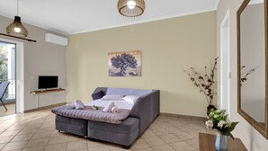 A modern bedroom with a sofa bed, a flat-screen TV, a painting, and a vase with flowers. - Apartment 'Elaia  2' with Sea View, Wi-Fi and Air Conditioning (?e???da)