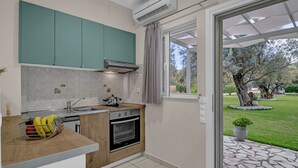 A modern kitchen with teal cabinets, a built-in oven, and a window overlooking a garden. - Studio Apartment 'Elaia  3' with Mountain View, Wi-Fi and Air Conditioning (?e???da)