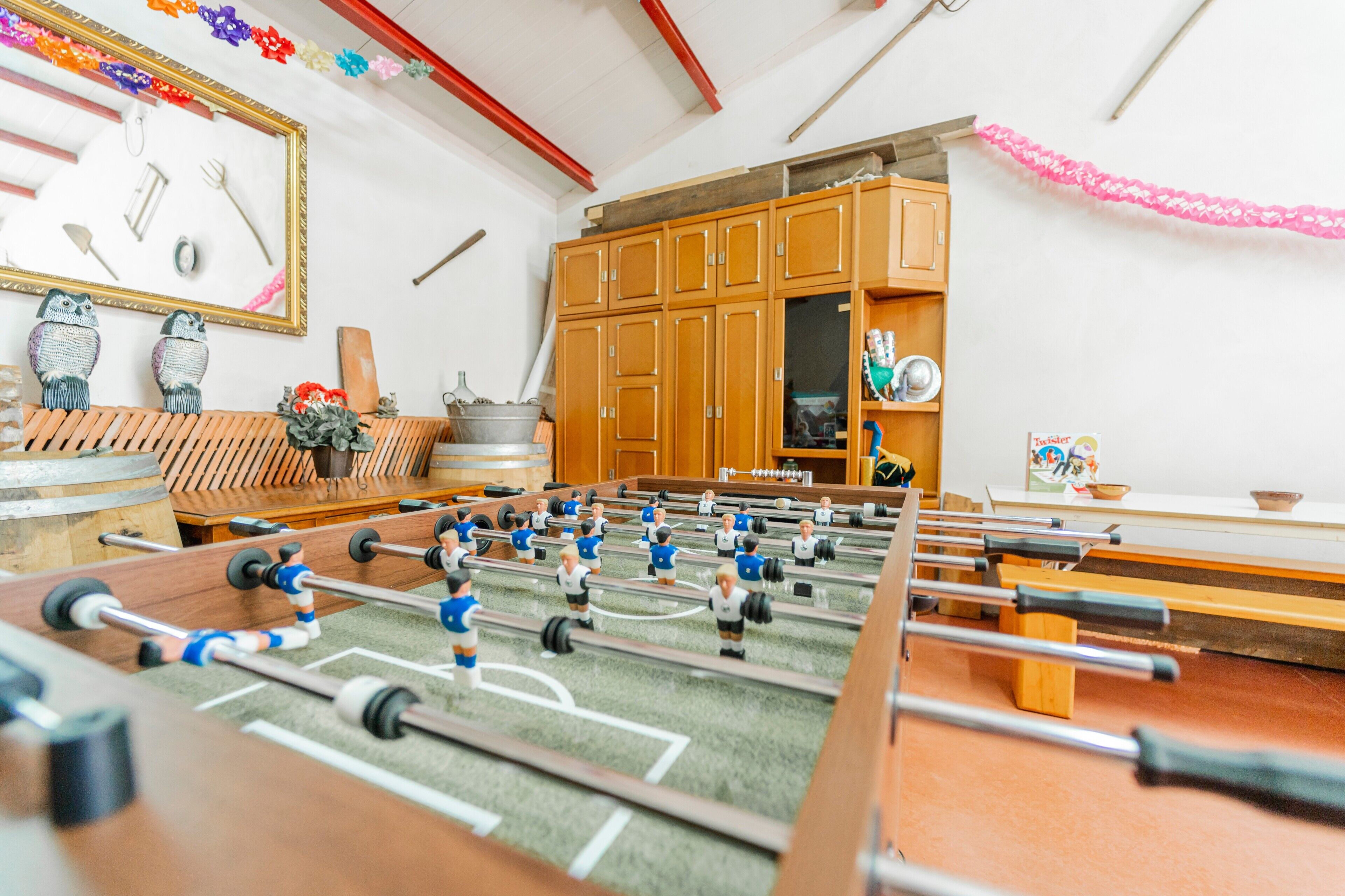 Une table de baby-foot dans une pièce avec des meubles en bois et un miroir au mur.