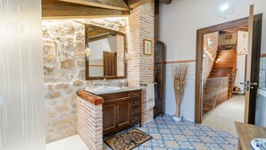 Un baño con pared de piedra, tocador de madera y espejo.