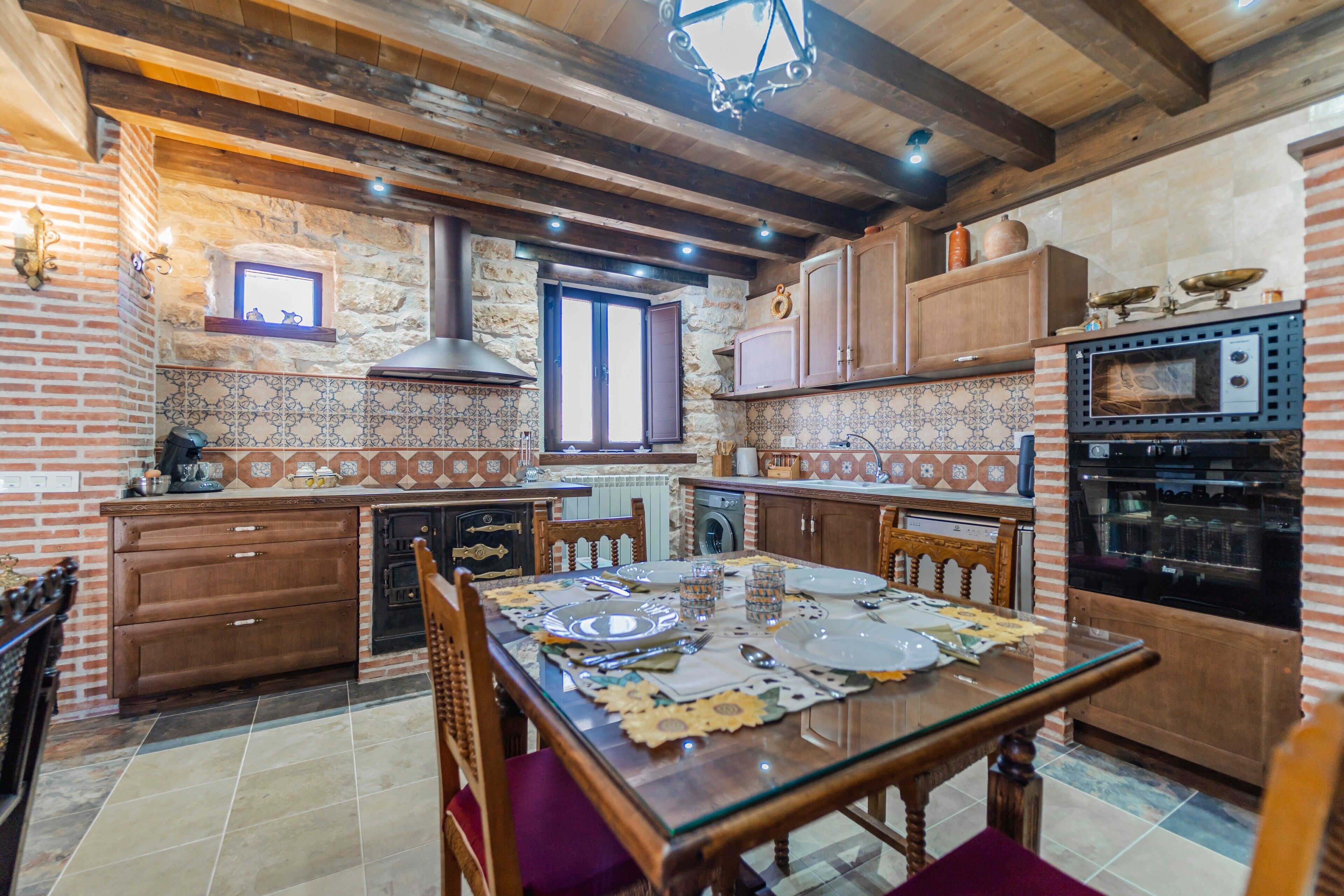 Une cuisine rustique avec des poutres apparentes, un mur en pierre et un poêle traditionnel.