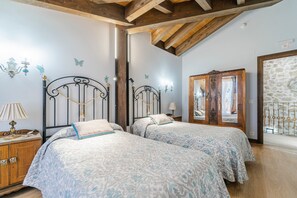 Ein Schlafzimmer mit zwei Betten, Holzbalken, einem Spiegel und Schmetterlingsstickern an der Wand.