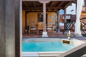 Hidromassagem com uma garrafa, cadeiras de madeira e uma parede de pedra.