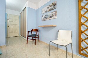 A hallway with a wooden chair, a cushioned chair, and a door.