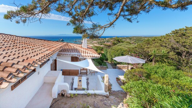 Eine Villa mit Ziegeldach, Außenbereich zum Sitzen und Meerblick.