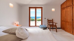 Ein Schlafzimmer mit Bett, Stuhl, Kleiderschrank und Meerblick.