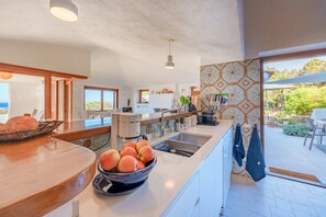 A modern kitchen with a large island, a dining area, and a view of the outdoors.