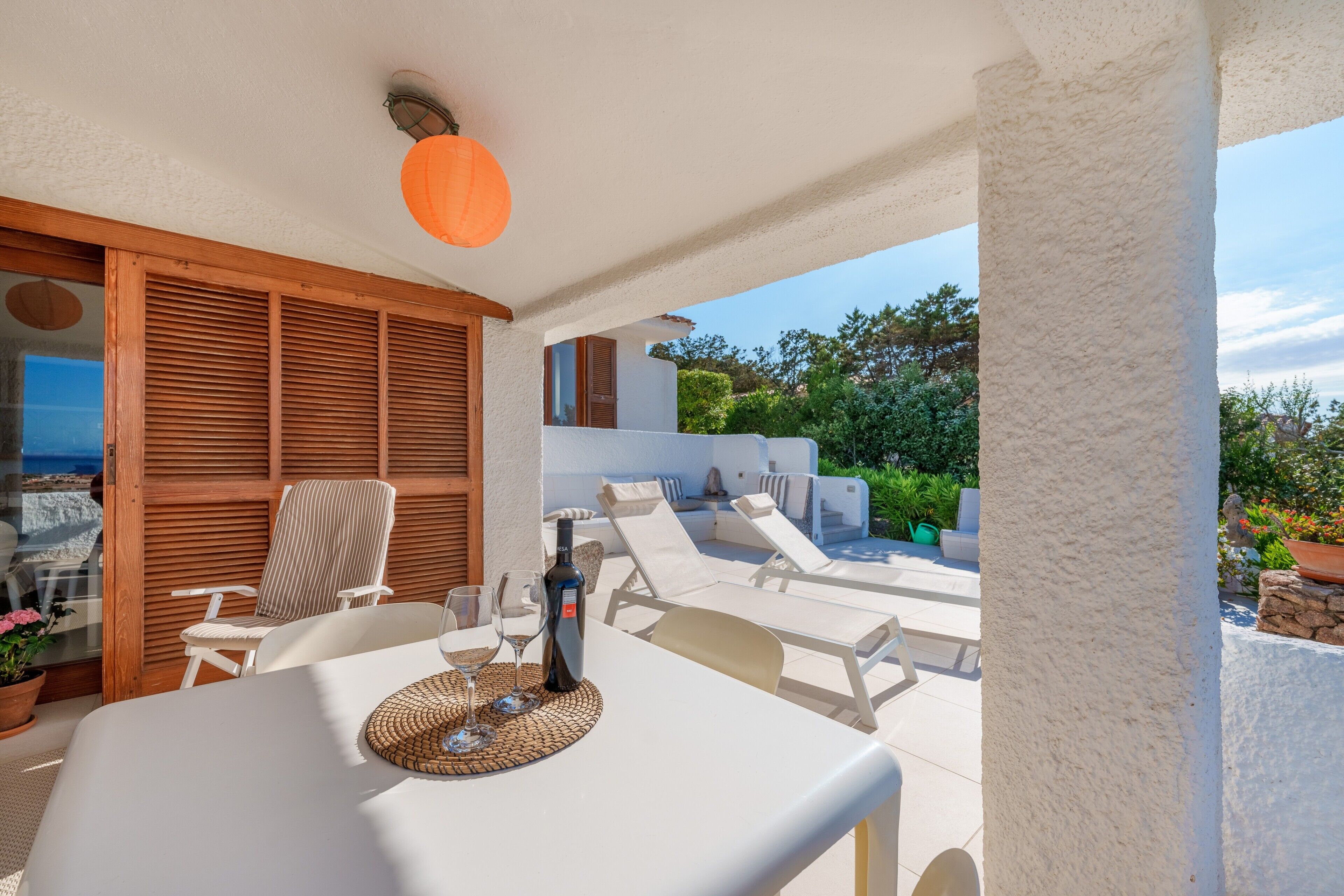 Eine Terrasse im Freien mit Tisch, Stühlen und einer Weinflasche.