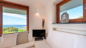 Ein Zimmer mit einem weißen Sofa, einem Flachbildfernseher und Meerblick.