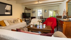 Ein gemütliches Wohnzimmer mit einer Couch, einem Holztisch, einem Fernseher und einem roten Sessel.