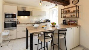 Eine moderne Küche mit Holzbalken, einer zentralen Kochinsel mit Stühlen, einer Mikrowelle, einem Backofen und einem Spülbecken.