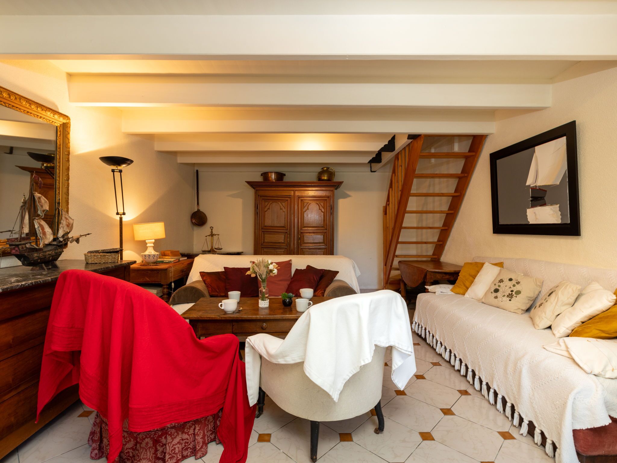 Une pièce confortable avec un lit, un canapé, une table à manger avec des chaises, un meuble en bois et un escalier menant à un niveau supérieur.