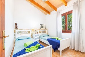 Une chambre avec deux lits simples, un plafond en bois, une fenêtre avec des rideaux et une porte.