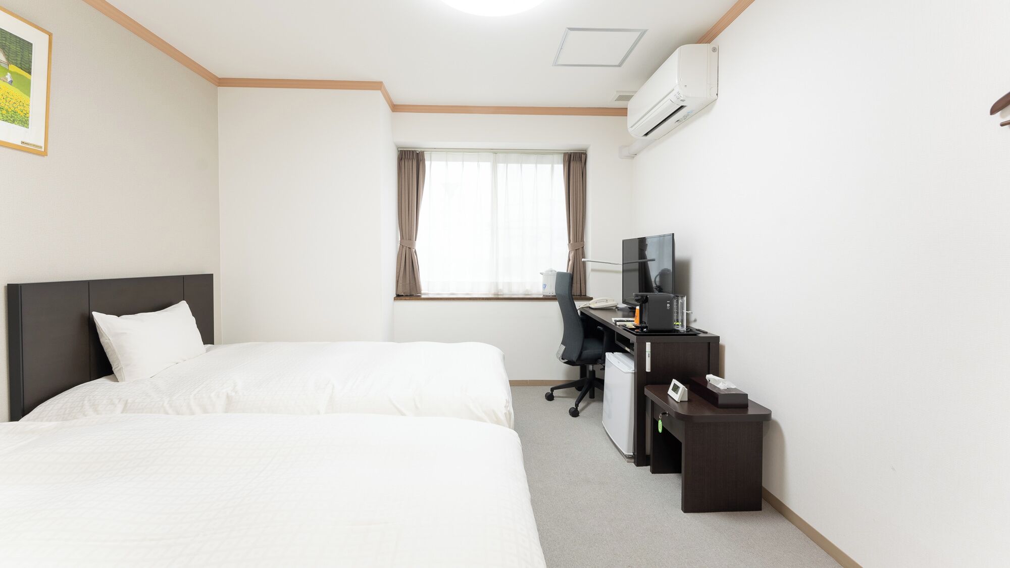 Une chambre d’hôtel équipée d’un lit, d’un bureau avec un ordinateur, d’une télévision et d’un climatiseur.