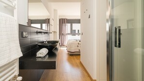 Une salle de bain moderne avec un plan de toilette noir, une serviette blanche et une cabine de douche en verre.
