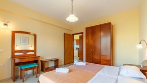 Une chambre à coucher comprenant un lit, un bureau en bois, un banc, une armoire et un miroir.