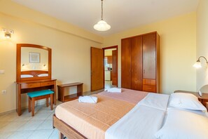 Un dormitorio con cama, escritorio de madera, banco, armario y espejo.
