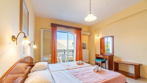 Une chambre d’hôtel avec un grand lit, un bureau, une chaise, un balcon et une vue sur l’extérieur.