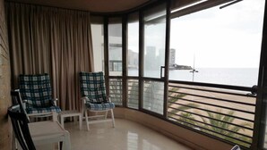 Un balcon avec deux chaises, une table et une vue sur la mer.