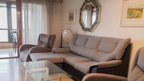 Un salon moderne avec un canapé d’angle, une table basse en verre et un miroir décoratif.