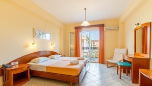 Une chambre d’hôtel avec un lit double, un bureau, une chaise, une petite table, un téléphone, un miroir et une vue sur l’extérieur.