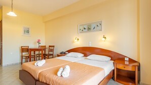 Une chambre d’hôtel avec un lit double, une table de chevet en bois, un bureau avec des chaises et un luminaire fixé au mur.