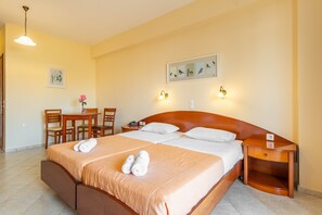Ein Hotelzimmer mit Doppelbett, Nachttisch aus Holz, Schreibtisch mit Stühlen und einer Wandleuchte.