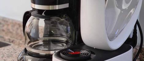 A coffee maker with a glass carafe and a white drip tray on a granite countertop.