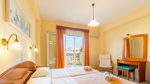 Ein Hotelzimmer mit Bett, Schreibtisch, Stuhl, Spiegel und einem Balkon mit Vorhängen.