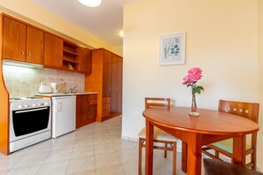 Une cuisine avec des meubles de rangement en bois, un fourneau blanc et une table à manger avec des chaises.