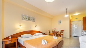 Une chambre d’hôtel comprenant un lit, des tables de chevet, un bureau, des chaises et une petite table sur laquelle est posé un vase.